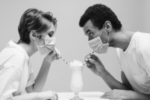 Couple masqué mangeant une glace à la paille